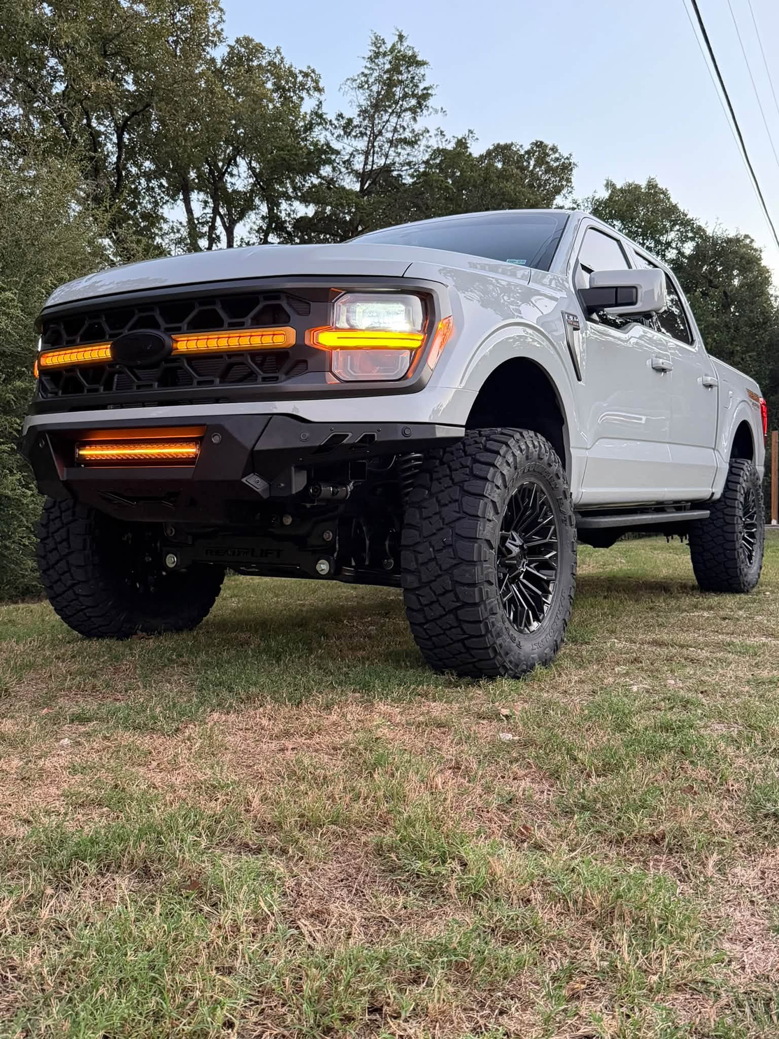 Front three-quarter view of the white 2026 Ford F-150 Tremor with amber running lights and 37-inch Toyo tires.